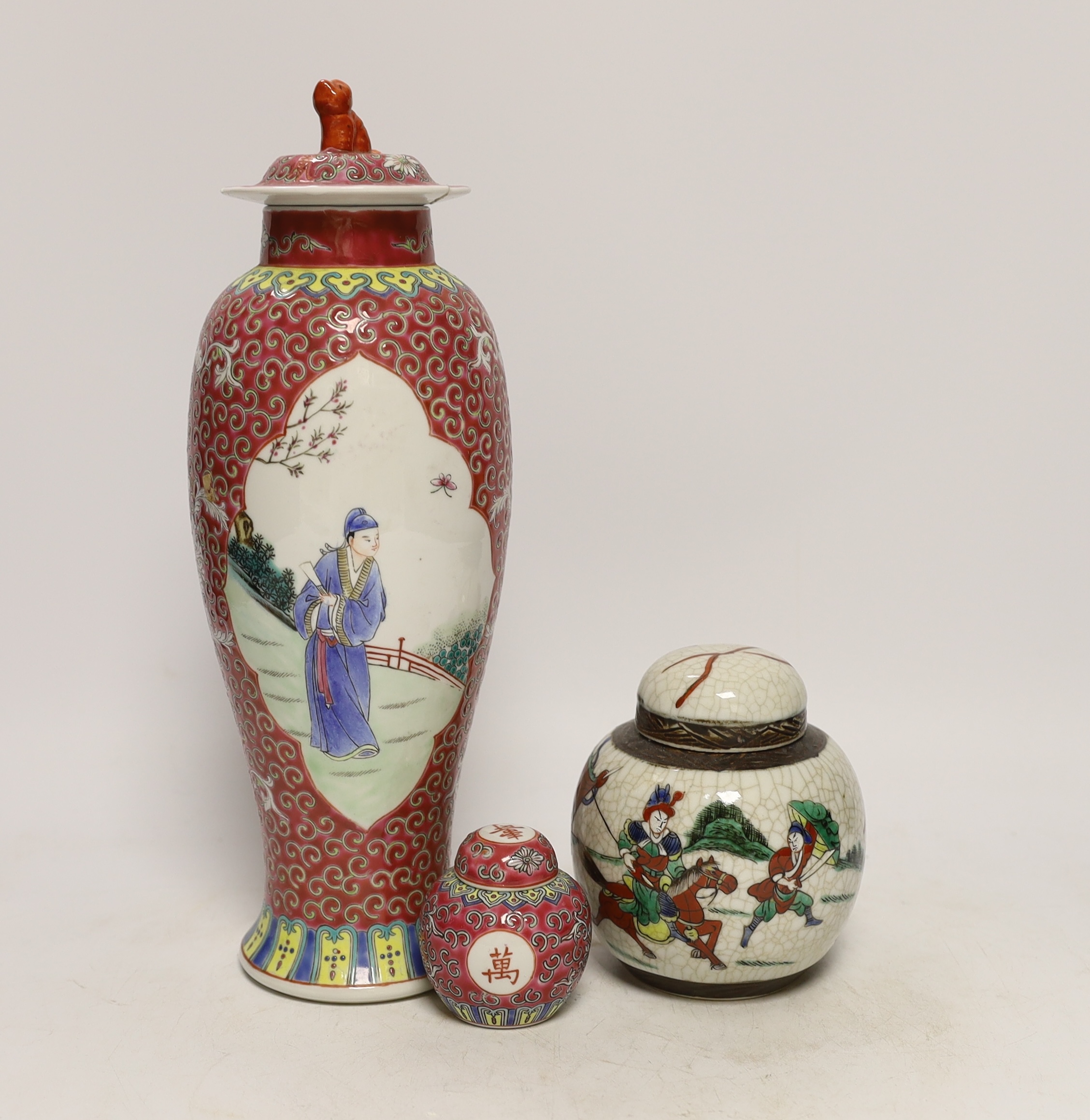 An early 20th century Chinese famille rose vase and cover, similar small jar and cover and a famille verte crackleglaze jar and cover, tallest 31cm